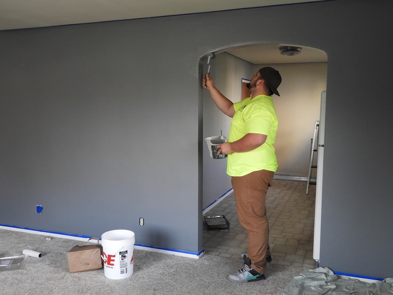 A plasterer in a hi-vis shirt working round an archway in a room being renovated