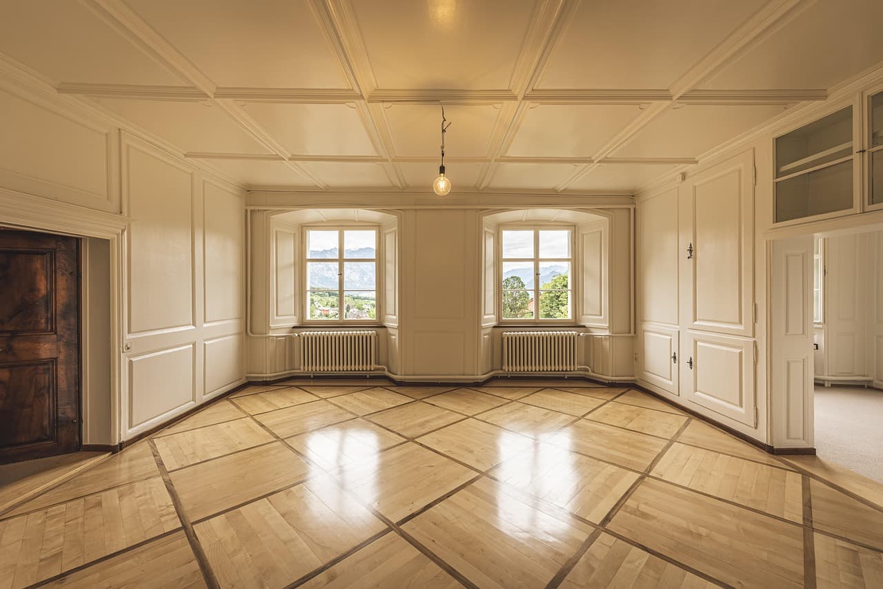 An empty, freshly finished room with smooth white walls and ceiling and two windows